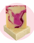 Two rectangular bars of handmade soap stacked, with one standing upright on top. The top bar has a marbled swirl pattern of cream, yellow, and magenta pink, while the bottom bar is solid cream.