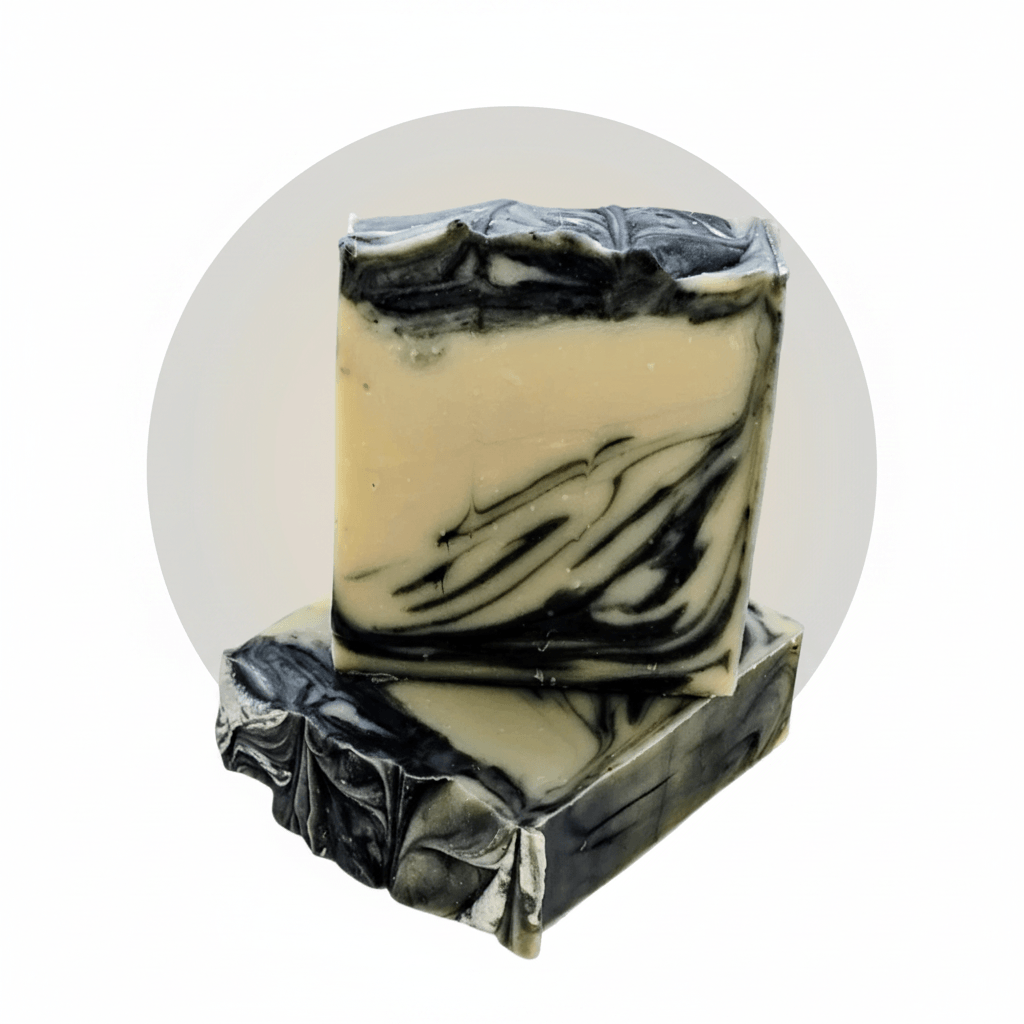 Two stacked rectangular bars of handmade soap with a cream-colored base and black marbled swirls, set against a white background with a light gray circular backdrop.