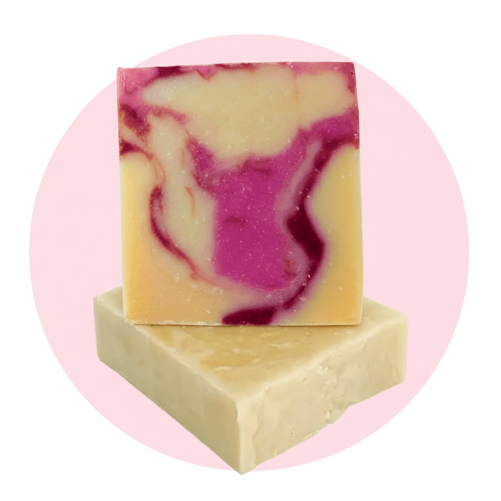 Two rectangular bars of handmade soap stacked, with one standing upright on top. The top bar has a marbled swirl pattern of cream, yellow, and magenta pink, while the bottom bar is solid cream.